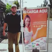 hombre afuera de su negocio sosteniendo una lona cobrando servicios en el estado de mexico